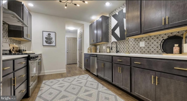 kitchen featuring dark brown cabinetry, sink, wall chimney exhaust hood, stainless steel appliances, and hardwood / wood-style flooring