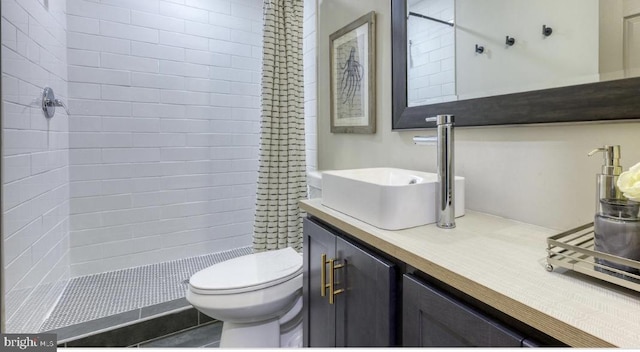 bathroom featuring a tile shower, vanity, and toilet