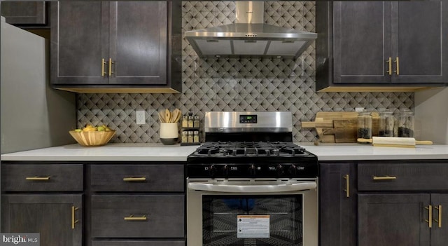 kitchen with tasteful backsplash, dark brown cabinetry, wall chimney exhaust hood, and stainless steel gas range