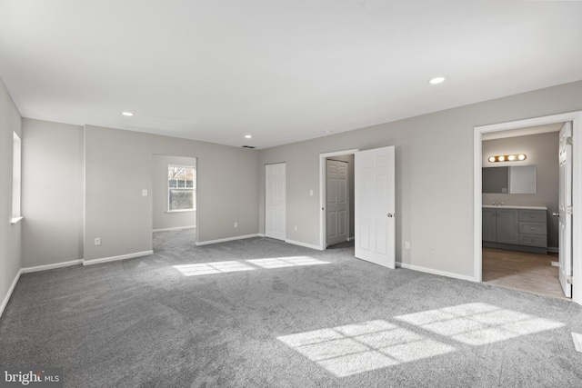 unfurnished bedroom with connected bathroom and light colored carpet