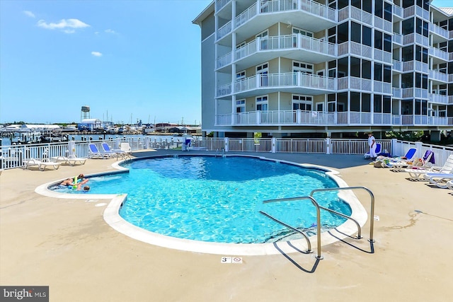 view of swimming pool featuring a patio and a water view