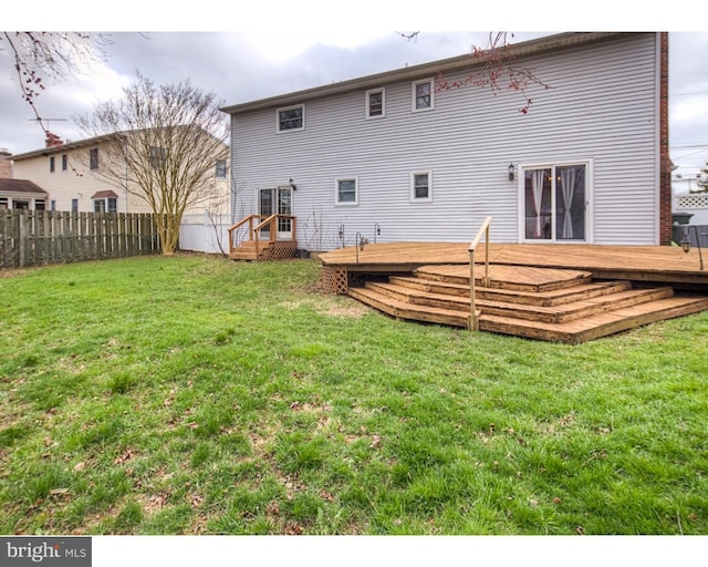 back of house featuring a deck and a lawn