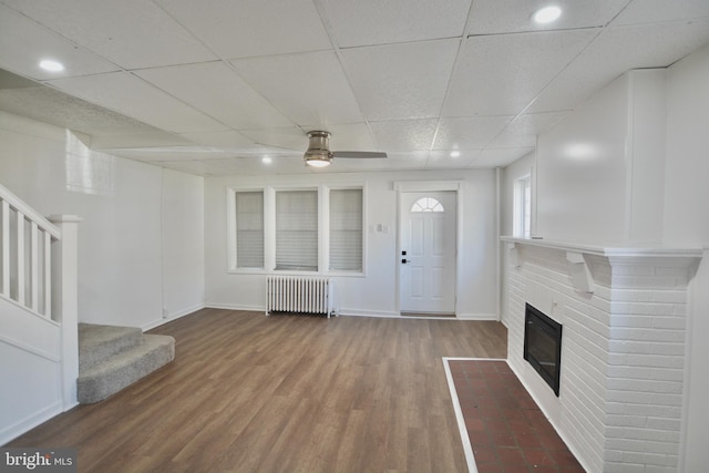 unfurnished living room featuring hardwood / wood-style flooring, a paneled ceiling, ceiling fan, and radiator