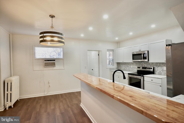 kitchen featuring butcher block countertops, appliances with stainless steel finishes, a healthy amount of sunlight, and radiator