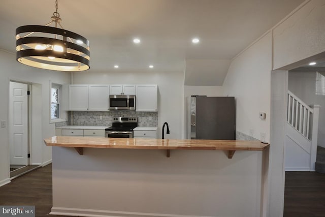 kitchen with dark wood-type flooring, wooden counters, a chandelier, white cabinets, and appliances with stainless steel finishes