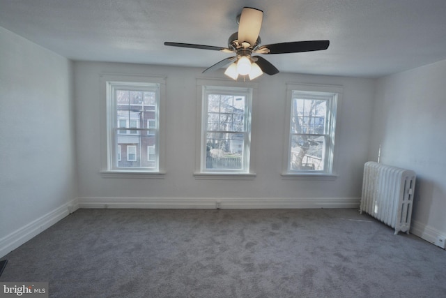 spare room featuring carpet floors, radiator, a healthy amount of sunlight, and ceiling fan