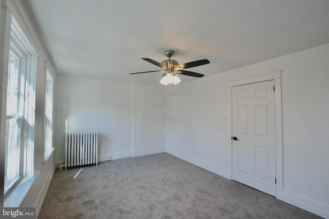 empty room featuring plenty of natural light, light carpet, and radiator