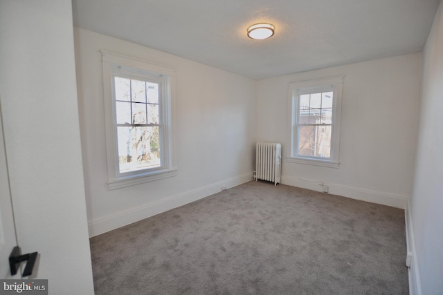 carpeted spare room featuring plenty of natural light and radiator