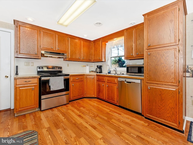 kitchen with stainless steel appliances, light hardwood / wood-style flooring, and sink