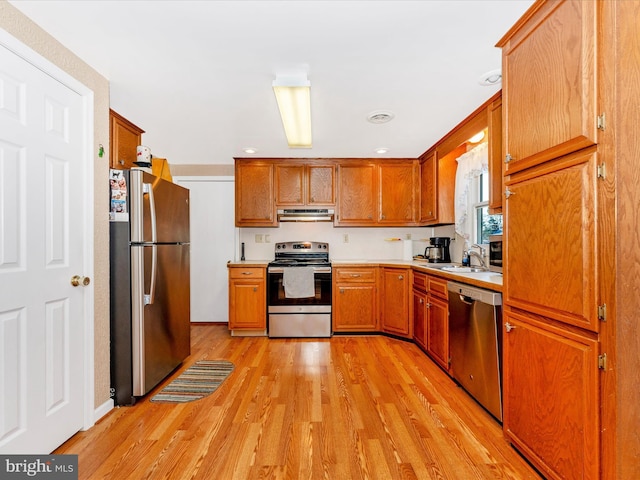 kitchen with appliances with stainless steel finishes, light wood-type flooring, and sink