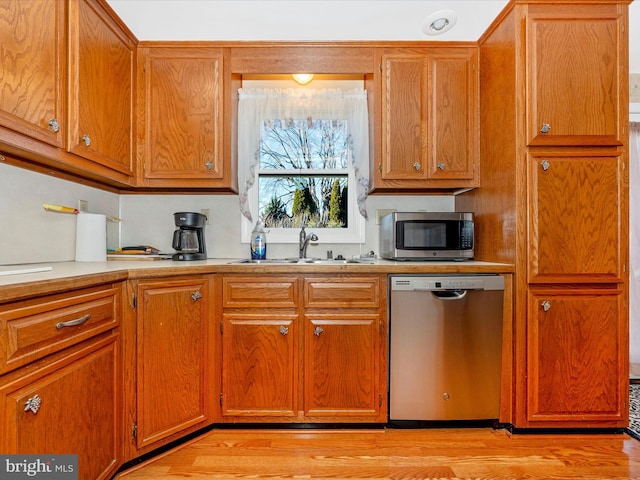 kitchen with stainless steel appliances, light hardwood / wood-style floors, and sink