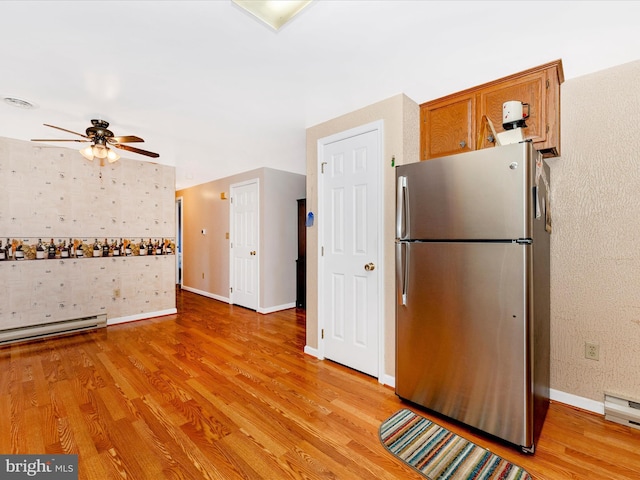 kitchen with stainless steel fridge, light hardwood / wood-style flooring, baseboard heating, and ceiling fan