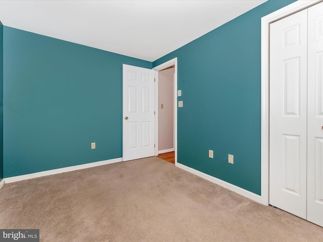 unfurnished bedroom with light carpet and a closet