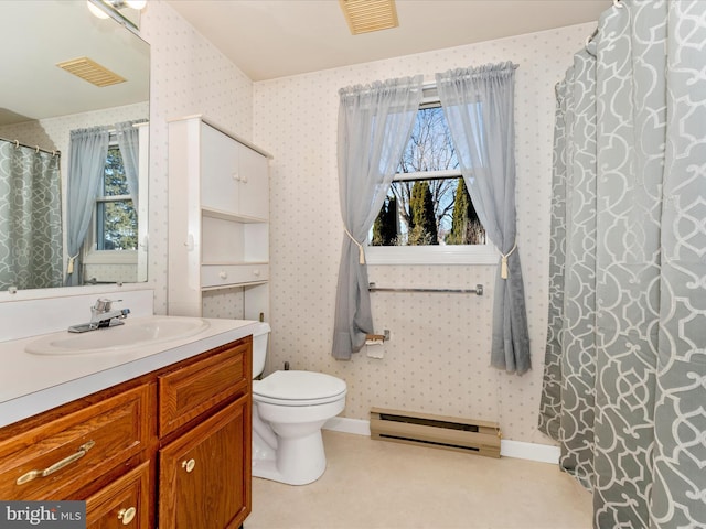 bathroom with vanity, toilet, baseboard heating, and a healthy amount of sunlight