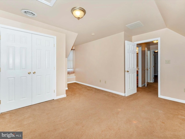 unfurnished bedroom with a closet, light colored carpet, and lofted ceiling