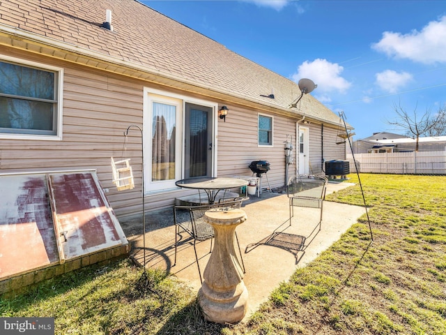 rear view of house with central air condition unit and a lawn