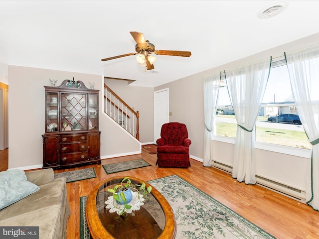 living room with ceiling fan, hardwood / wood-style floors, and a baseboard heating unit