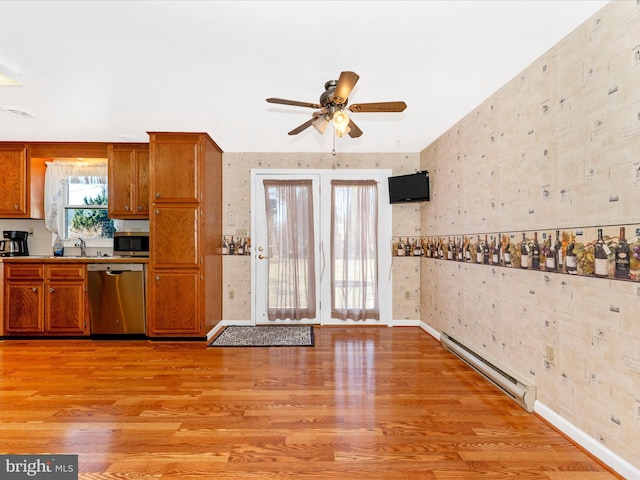 kitchen featuring appliances with stainless steel finishes, ceiling fan, a baseboard heating unit, sink, and light hardwood / wood-style floors