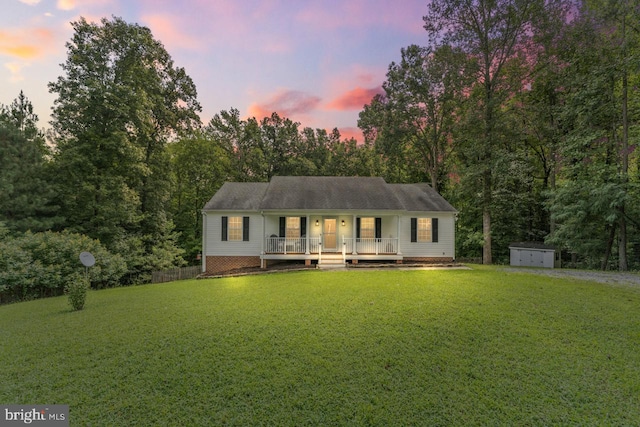 view of front of property with covered porch, a storage shed, and a lawn