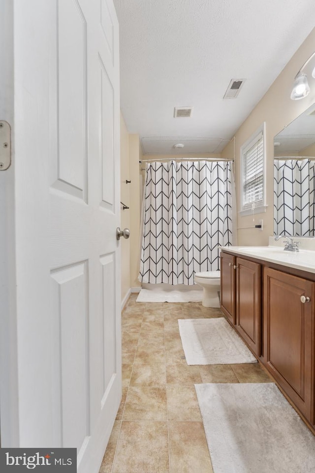 bathroom with vanity, a shower with curtain, tile patterned flooring, toilet, and a textured ceiling