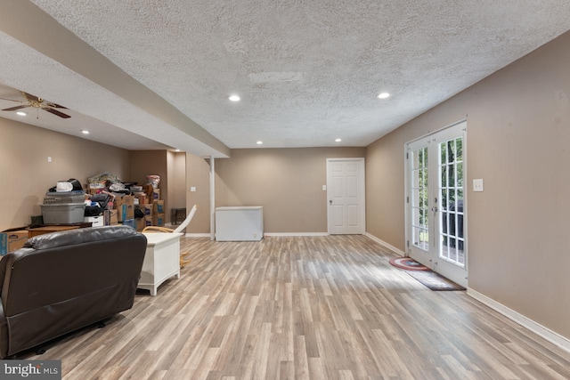 living room with ceiling fan, french doors, a textured ceiling, and light hardwood / wood-style flooring