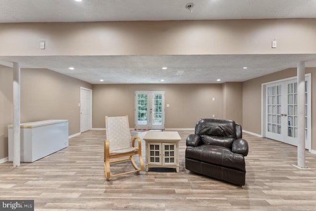 sitting room with french doors, light hardwood / wood-style floors, and a textured ceiling