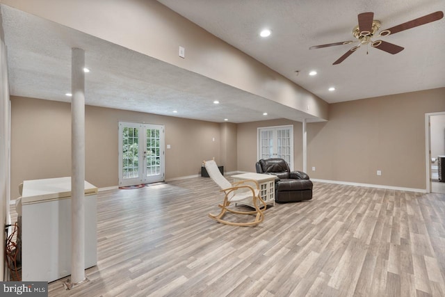 living area featuring ceiling fan, french doors, a textured ceiling, and light hardwood / wood-style flooring