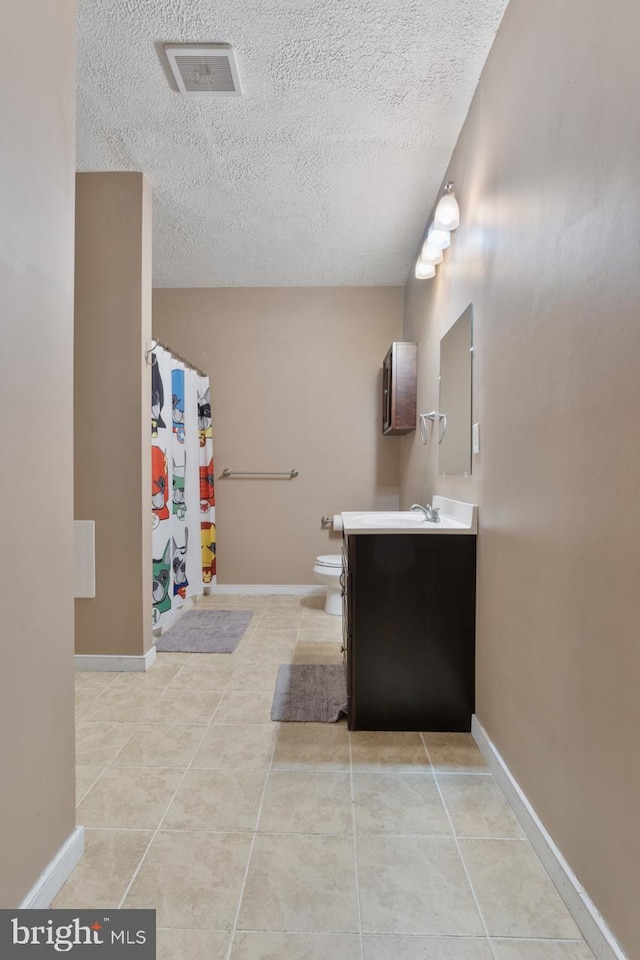 bathroom featuring toilet, a textured ceiling, vanity, and tile patterned floors