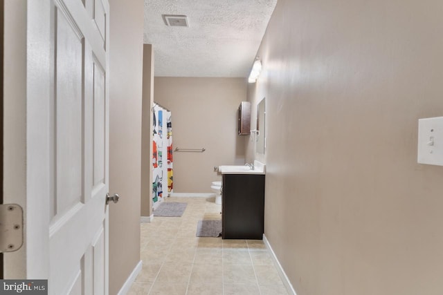 bathroom featuring tile patterned flooring, a textured ceiling, vanity, and toilet