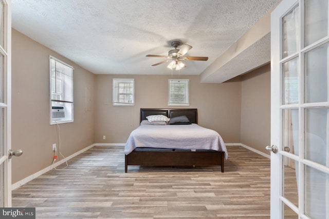 bedroom featuring a textured ceiling, light hardwood / wood-style flooring, ceiling fan, and cooling unit