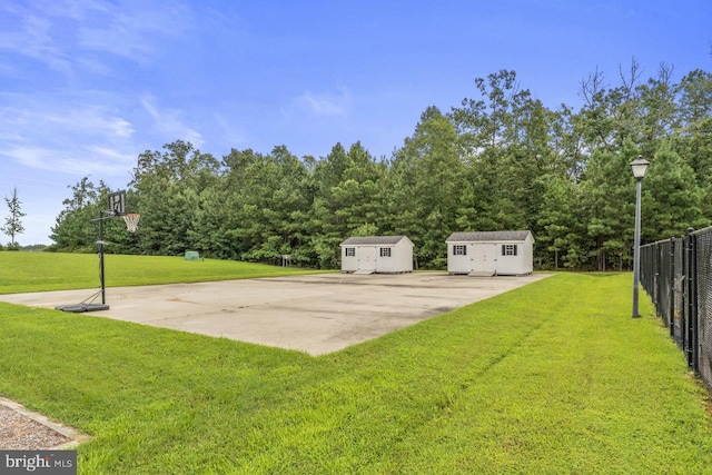 view of yard featuring basketball hoop and a storage shed