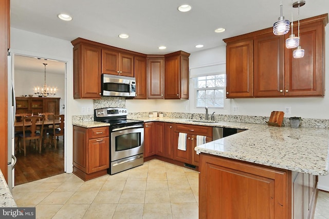 kitchen with sink, decorative light fixtures, stainless steel appliances, and kitchen peninsula