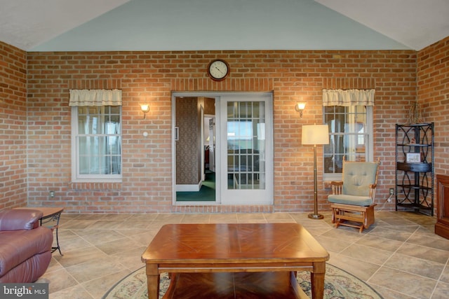 living room featuring brick wall and lofted ceiling