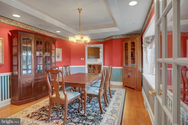 dining room with a tray ceiling, crown molding, light hardwood / wood-style flooring, and an inviting chandelier