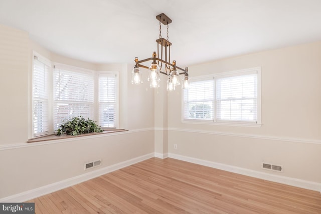 unfurnished room featuring wood finished floors, visible vents, and baseboards