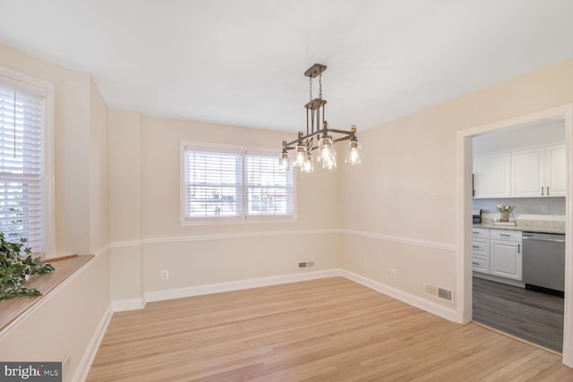 unfurnished dining area with a notable chandelier, visible vents, light wood-style flooring, and baseboards