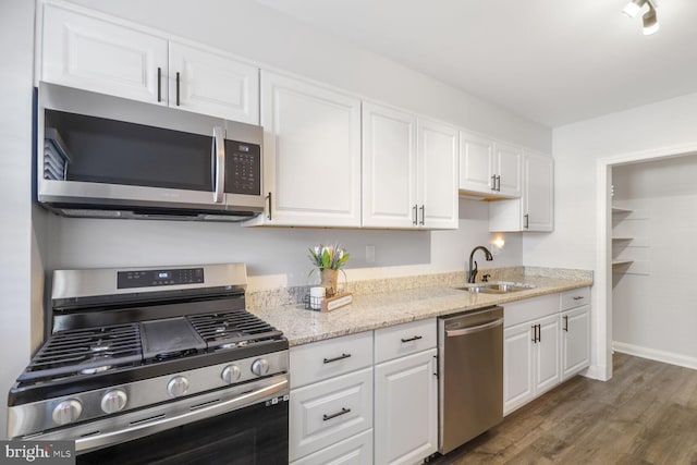 kitchen featuring a sink, white cabinets, wood finished floors, and stainless steel appliances