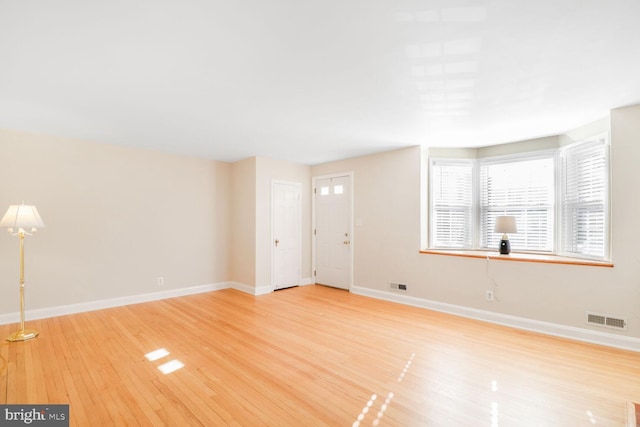 unfurnished living room featuring visible vents, baseboards, and light wood finished floors