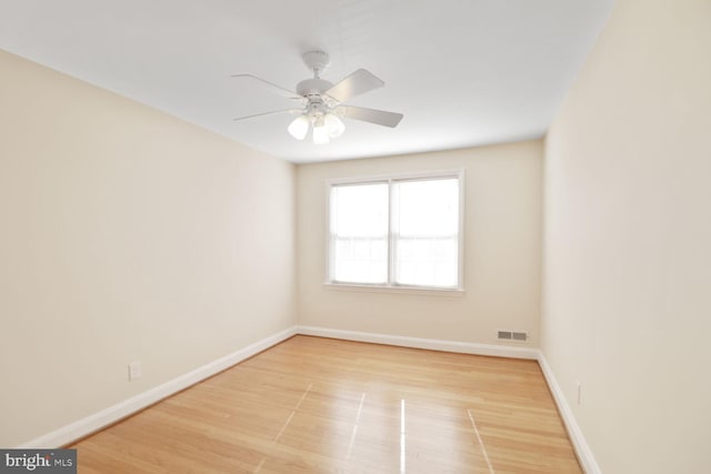 empty room with a ceiling fan, wood finished floors, visible vents, and baseboards