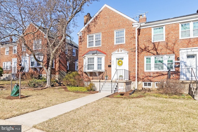 multi unit property with a front lawn, brick siding, and a chimney