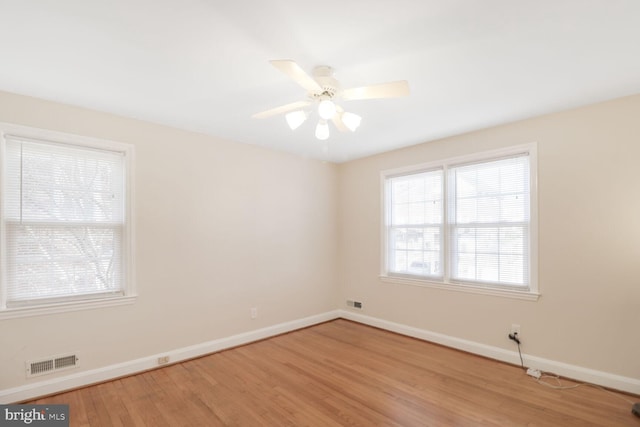 spare room with ceiling fan, light wood-style floors, visible vents, and baseboards