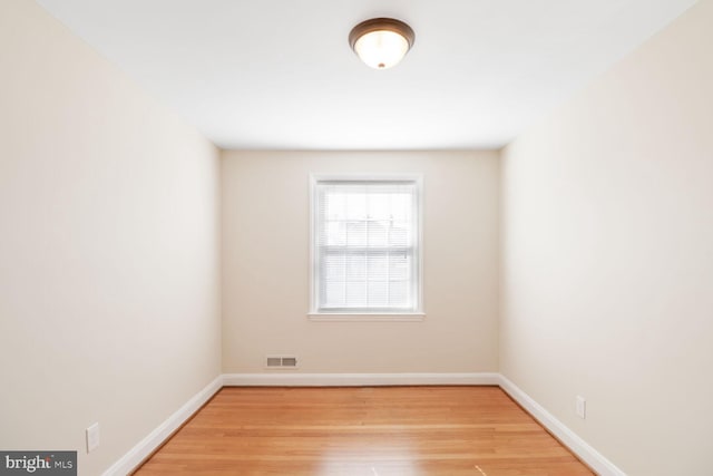 empty room featuring visible vents, baseboards, and wood finished floors