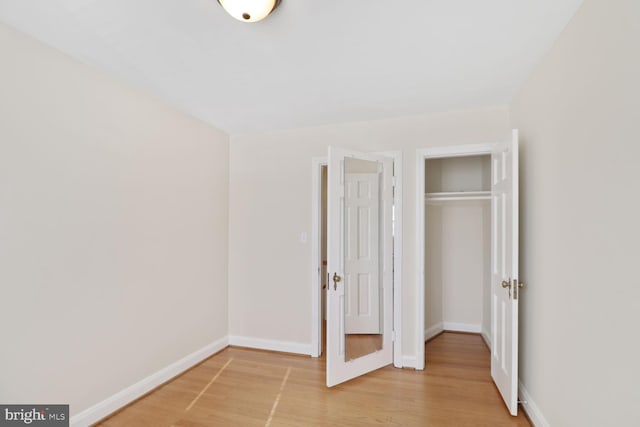 unfurnished bedroom featuring a closet, baseboards, and light wood finished floors