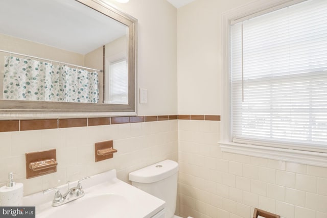 bathroom featuring curtained shower, toilet, tile walls, and vanity