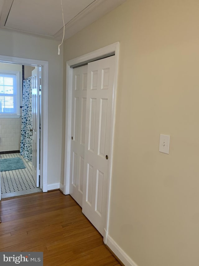 corridor featuring baseboards, attic access, and wood finished floors