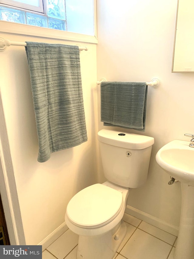 half bathroom featuring baseboards, toilet, and tile patterned flooring