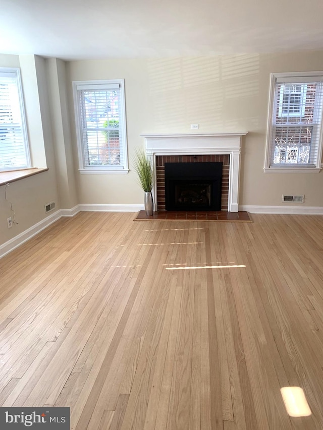 unfurnished living room featuring visible vents, baseboards, wood finished floors, and a fireplace