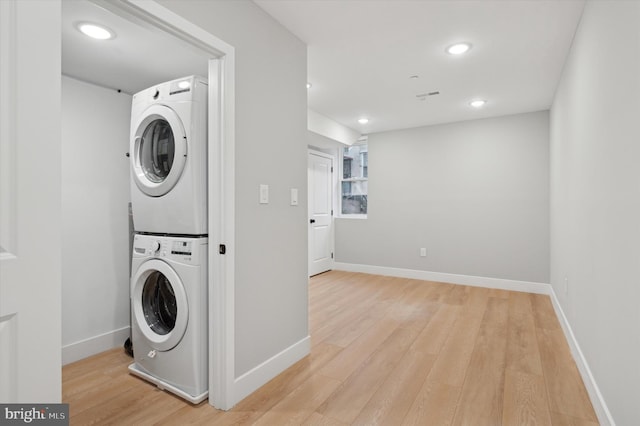 laundry room featuring stacked washer and dryer and light hardwood / wood-style floors