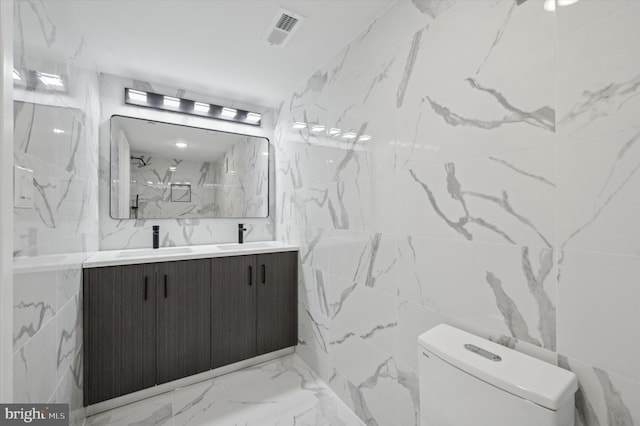 bathroom with a shower, vanity, tile walls, and toilet