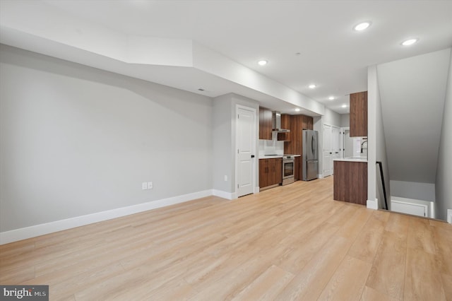 kitchen with wall chimney exhaust hood, light hardwood / wood-style floors, sink, and stainless steel appliances